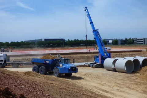 Grue télescopique et tuyaux d'assainissement en approvisionnement sur chantier