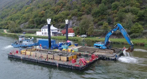 Pelle hydraulique travaillant depuis un ponton poussé sur une rivière