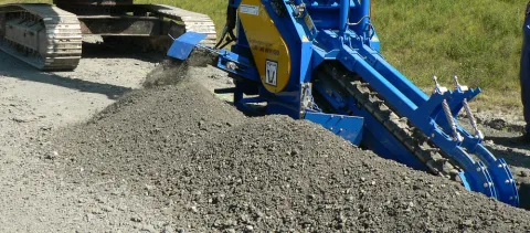 Trancheuse ouvrant une tranchée dans un sol caillouteux