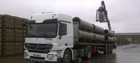 Plateau équipé d'une grue auxiliaire chargé de canalisations