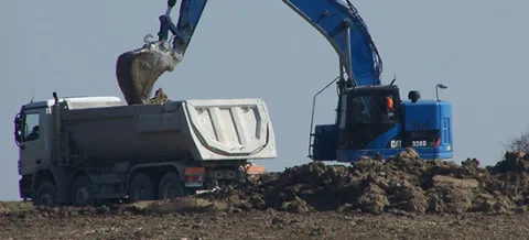 Porteur benne chargé par une pelle sur un chantier